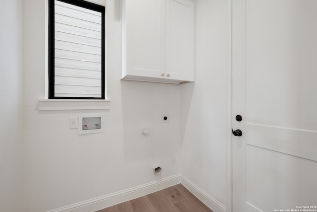 clothes washing area with hookup for an electric dryer, light hardwood / wood-style flooring, plenty of natural light, and cabinets