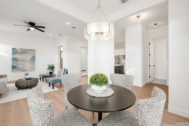 dining room featuring beam ceiling, light hardwood / wood-style flooring, and ceiling fan with notable chandelier