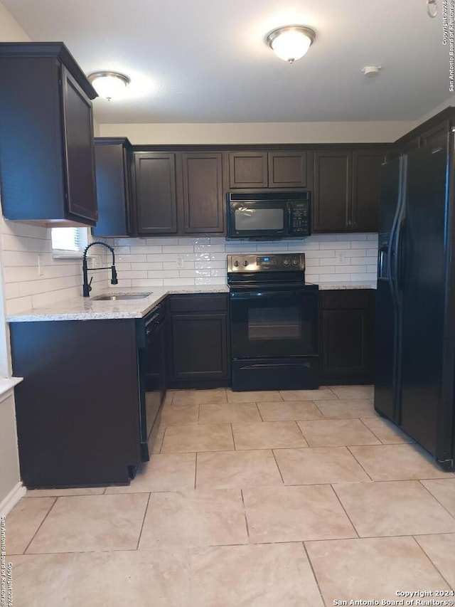 kitchen with light stone countertops, decorative backsplash, sink, and black appliances