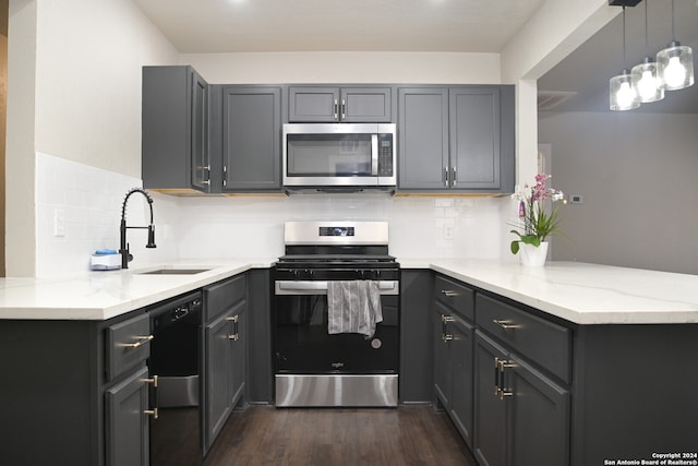 kitchen featuring sink, appliances with stainless steel finishes, decorative light fixtures, kitchen peninsula, and dark hardwood / wood-style floors