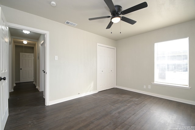 unfurnished bedroom featuring a closet, ceiling fan, and dark wood-type flooring