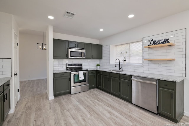 kitchen featuring light stone countertops, appliances with stainless steel finishes, decorative backsplash, sink, and light hardwood / wood-style floors