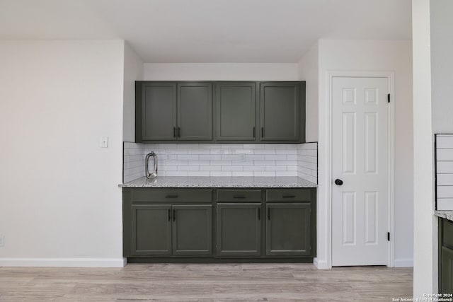 kitchen with light stone countertops, backsplash, and light hardwood / wood-style flooring