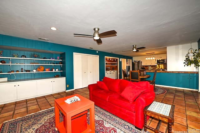 living room with ceiling fan, built in features, and dark tile patterned floors