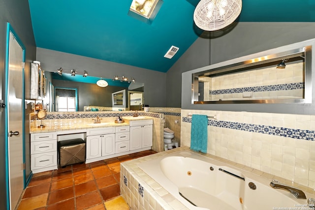 bathroom with tile patterned floors, vanity, vaulted ceiling, a relaxing tiled tub, and toilet