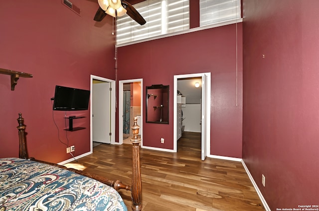 bedroom featuring a high ceiling, a walk in closet, ceiling fan, connected bathroom, and wood-type flooring