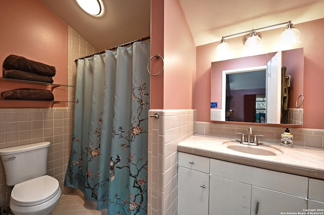 bathroom with vanity, vaulted ceiling, tile walls, tile patterned flooring, and toilet