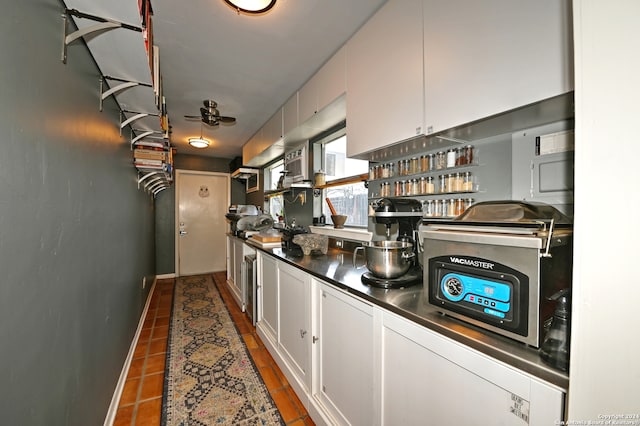 interior space featuring white cabinets, ceiling fan, and dark tile patterned floors