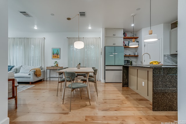 kitchen featuring white fridge, light hardwood / wood-style flooring, hanging light fixtures, and sink