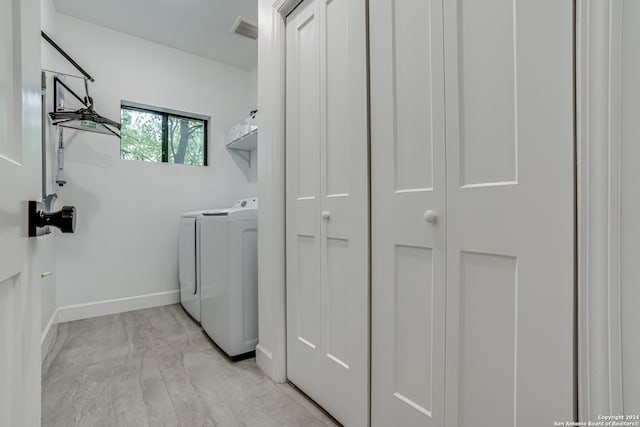 clothes washing area with washing machine and dryer and light hardwood / wood-style floors