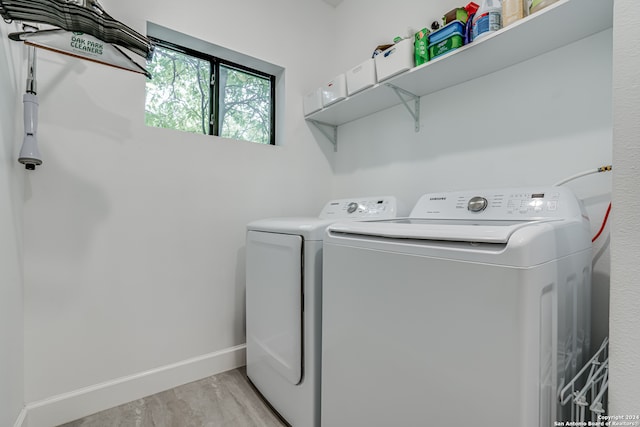 clothes washing area with separate washer and dryer and light hardwood / wood-style floors