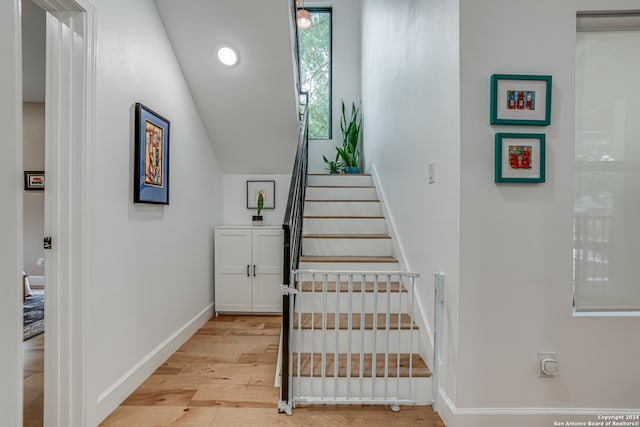 staircase featuring wood-type flooring and vaulted ceiling