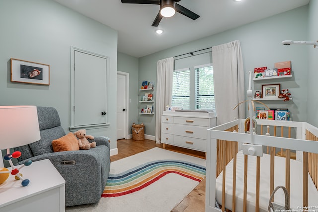 bedroom featuring a nursery area and ceiling fan