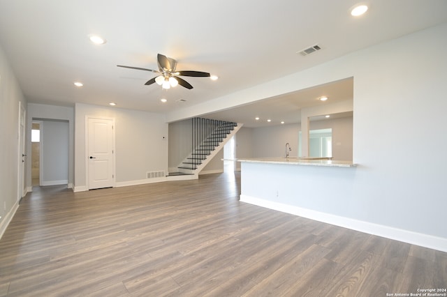 unfurnished living room with ceiling fan and dark wood-type flooring