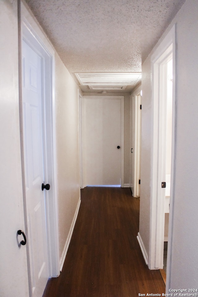 hallway featuring dark hardwood / wood-style flooring and a textured ceiling