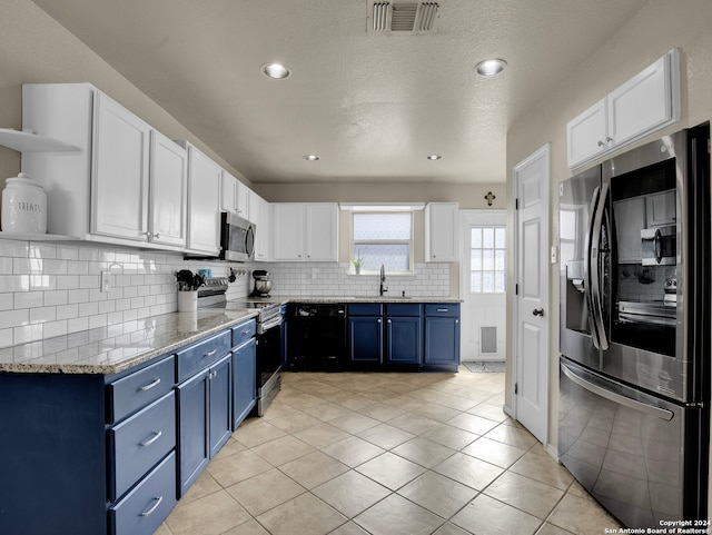 kitchen featuring blue cabinets, white cabinets, light tile patterned floors, and appliances with stainless steel finishes