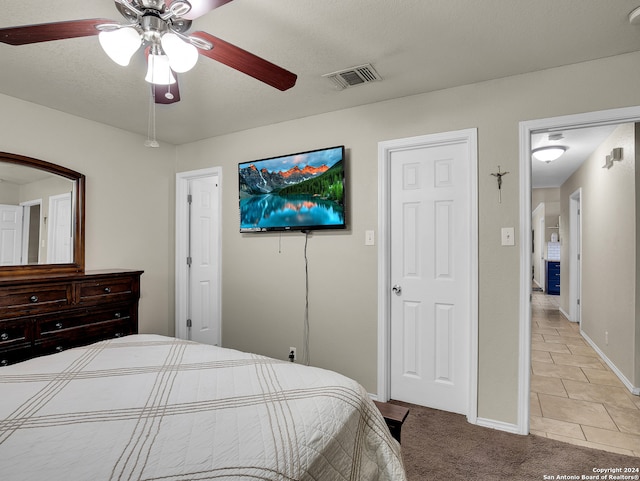 tiled bedroom featuring ceiling fan and a textured ceiling