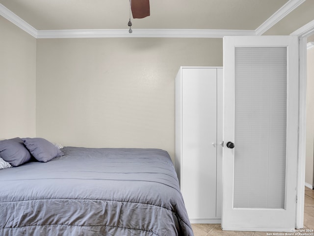 tiled bedroom with ceiling fan and crown molding