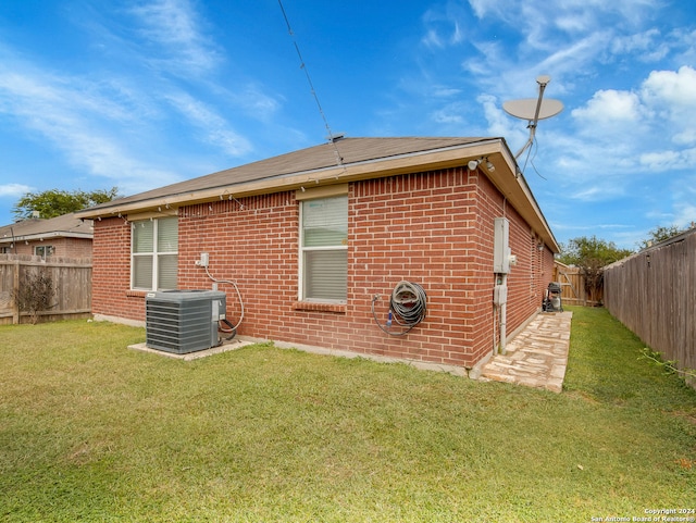 rear view of property featuring a yard and central AC unit