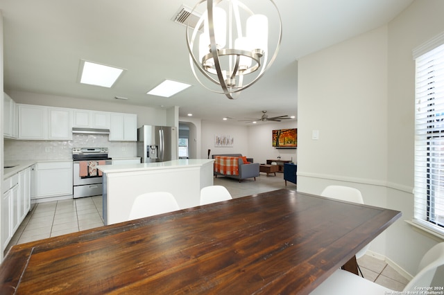 tiled dining space featuring plenty of natural light and ceiling fan with notable chandelier