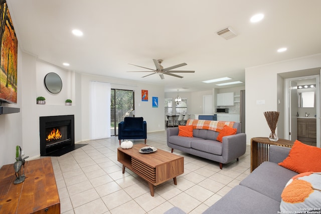 living room featuring ceiling fan, sink, light tile patterned floors, and crown molding