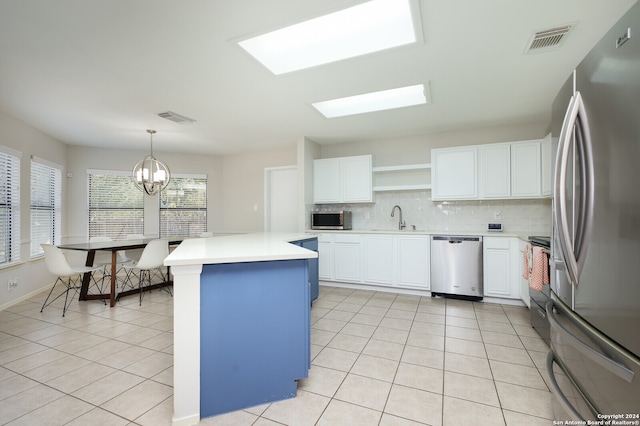 kitchen with pendant lighting, white cabinets, stainless steel appliances, and sink