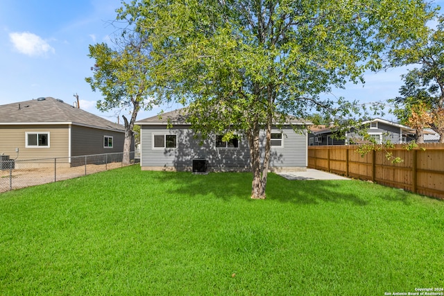 rear view of house featuring a lawn, central air condition unit, and a patio