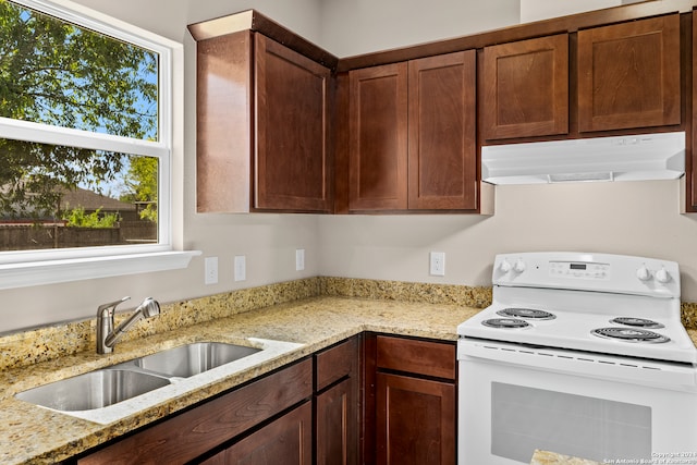 kitchen with light stone countertops, electric stove, and sink