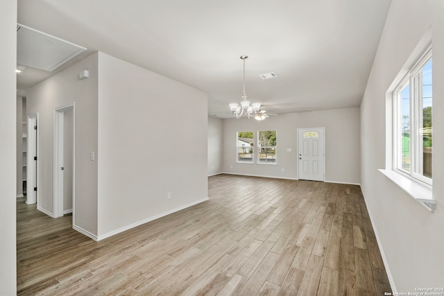 unfurnished room with light hardwood / wood-style flooring and ceiling fan with notable chandelier