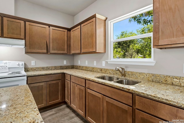 kitchen featuring white stove, dark hardwood / wood-style floors, light stone counters, and sink