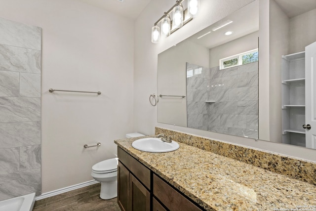 bathroom featuring tiled shower, toilet, vanity, and hardwood / wood-style flooring