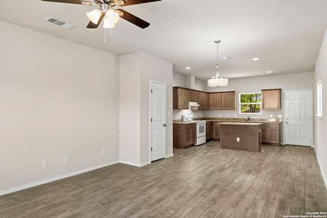 kitchen featuring pendant lighting, electric range, ceiling fan, a kitchen island, and wood-type flooring