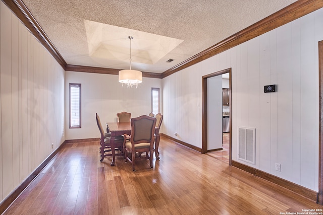 dining space with hardwood / wood-style floors, a textured ceiling, and ornamental molding