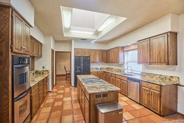 kitchen with appliances with stainless steel finishes, a center island, a textured ceiling, and sink