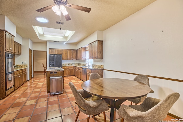 kitchen featuring a skylight, a textured ceiling, stainless steel appliances, a raised ceiling, and a center island