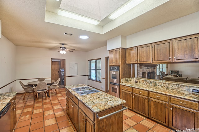 kitchen featuring a textured ceiling, ceiling fan, a center island, and stainless steel appliances