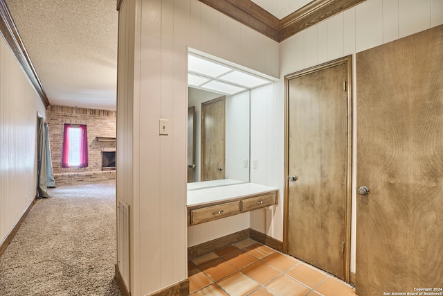 bathroom with a fireplace, a textured ceiling, tile patterned floors, and ornamental molding