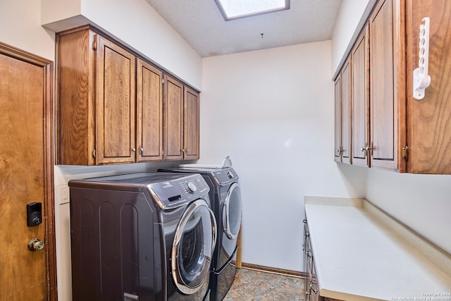 washroom featuring cabinets, a textured ceiling, and washing machine and clothes dryer