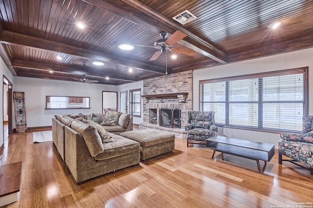 living room featuring beam ceiling, light wood-type flooring, wooden ceiling, and a fireplace