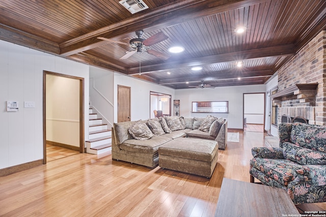 living room featuring beam ceiling, light hardwood / wood-style floors, wooden ceiling, and a fireplace