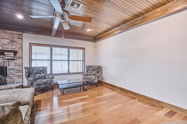 living area with a fireplace, light hardwood / wood-style flooring, ceiling fan, and wood ceiling