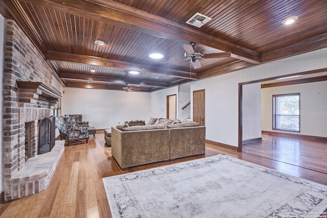 living room featuring beam ceiling, ceiling fan, a fireplace, wood ceiling, and light wood-type flooring