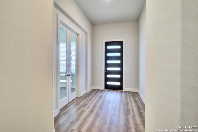 doorway to outside with wood finished floors, baseboards, and a textured wall