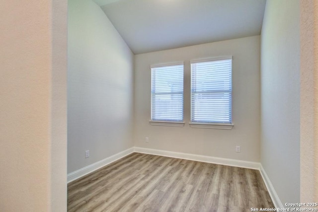 unfurnished room featuring lofted ceiling, wood finished floors, and baseboards