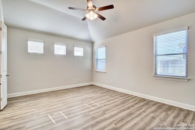 empty room with light wood finished floors, a ceiling fan, baseboards, and vaulted ceiling
