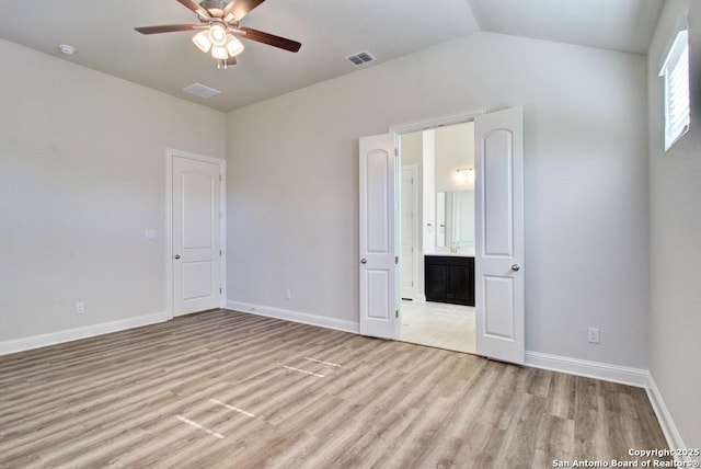 unfurnished bedroom featuring light wood-style floors, baseboards, ensuite bathroom, vaulted ceiling, and ceiling fan
