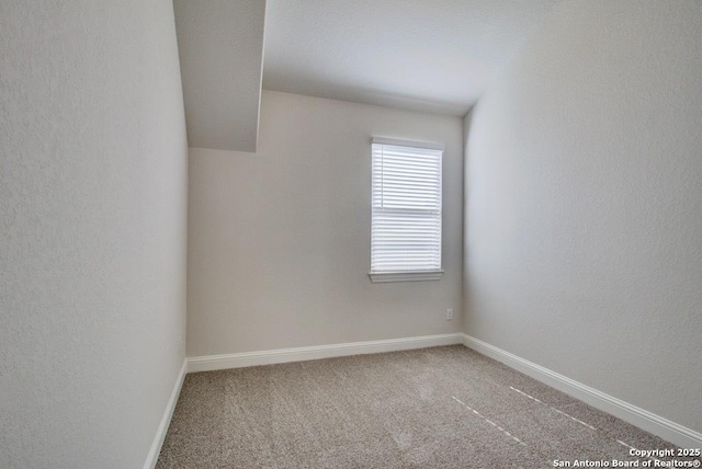 unfurnished room with carpet, baseboards, and a textured wall