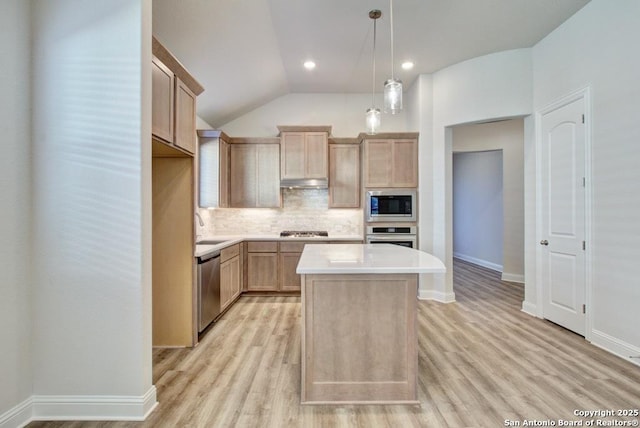 kitchen with stainless steel appliances, light brown cabinetry, a center island, tasteful backsplash, and light countertops