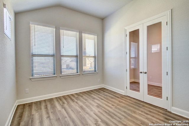 spare room with french doors, wood finished floors, baseboards, and lofted ceiling