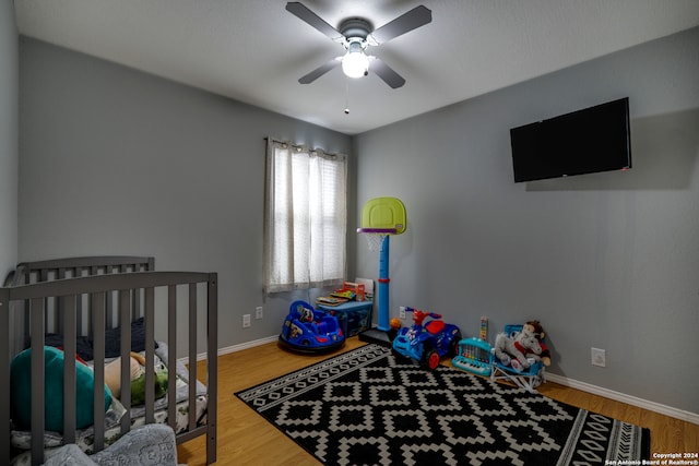 bedroom featuring a crib, hardwood / wood-style flooring, and ceiling fan